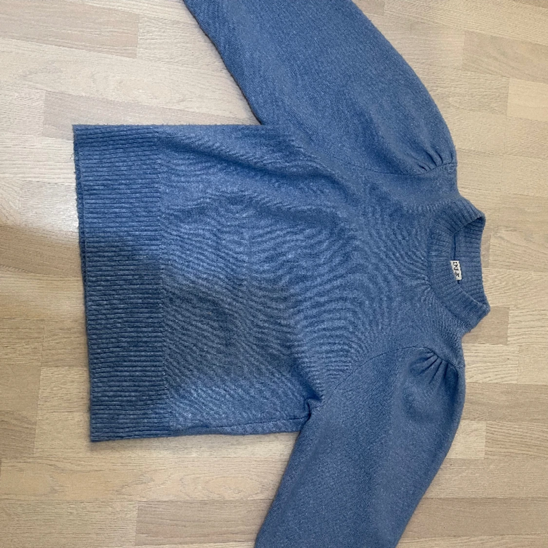 Blå stickad tröja med veck i axeln