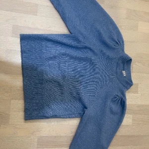 Blå stickad tröja med veck i axeln - Intresse koll på denna fina stickade tröjan, säljer då den ej komme till användning. Den är i nyskick och endast använd ett fåtal gånger. Den är i storlek Large men skulle säga att dne sitter mer som medium.