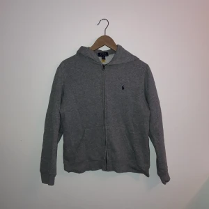 Ralph lauren zip hoodie - En bekväm grå hoodie från Polo Ralph Lauren. 9/10 skick lite nopprig men inget som syns när man har på sig den storlek L i barn nypris 1100 mitt pris 499