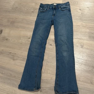 Blå jeans från Gina Tricot - Ett par blå jeans från Gina Young i storlek 152. Byxorna har fickor med knappar där bak.