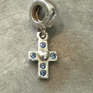 Pandora berlock - Superfint litet kors med ljusblå sten. 