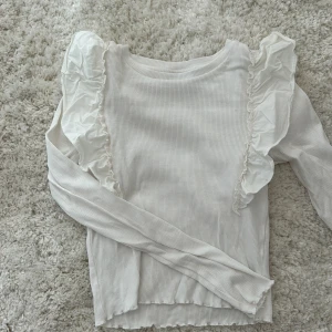 Fin tröja - Den är ribbad med bra kvalitet. Fina volanger och långärmad😀