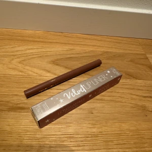 Velvet Lip Liner - En brun Velvet Lip Liner från Ciaté. Läppennan kommer i en elegant förpackning med stjärndekorationer och texten 'Velvet Lip Liner' tryckt på framsidan.