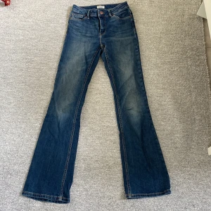 Blå jeans från Lindex - Ett par blå jeansbyxor från Lindex i storlek EUR 34 / UK 8. Byxorna har en klassisk femficksdesign och är tillverkade i ett slitstarkt denimtyg. Jeansen är bootcut. på sista bilden kan man se en liten defekt och det är att det har rivits upp lite men det är väldigt litet
