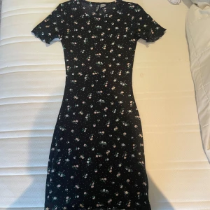 Svart blommig klänning  -  Säljer denna klänningen eftersom att den inte kommer till användning klänningen har använts två gånger så den är i fint fint skick 🤗🤗den är stretchig och skön i materialet