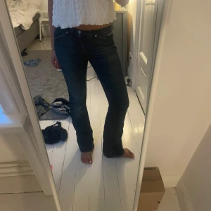 Mörkblå jeansbyxor - Ett par mörkblå jeansbyxor i storlek S. Byxorna har en tight passform upptill och blir vidare nedtill, vilket ger en bootcut-stil. Jeansen stängs med dragkedja och knapp. 