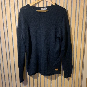 Stickad långärmad tröja - En stickad långärmad tröja från märket Jack and jones. Den är varm bekväm och snygg. Denna är i färgen mellan blå och svart samt att den är vintage och går inte att köpa längre. Inga defekter eller problem👍 Kontakta mig vid frågor 💯✅