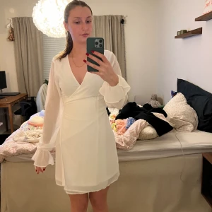 Klänning  - Vit omlottklänning som passar perfekt till studenten. Klänning har en grön liten fläck på sidan av sig vet ej om den går bort(se bild 2)💚😊