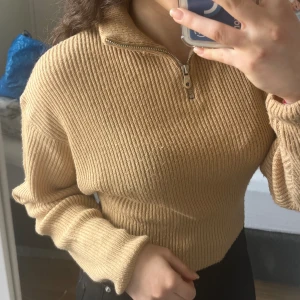 Stickad tröja  - En enkel men fin stickad tröja. Har en dragkedja som gör den extra unik. Den är bege/brun. 