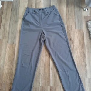 Raka byxor - Gråa högmidjade byxor, raka i modellen. Storlek 38. Använda fåtalet gånger så i fint skick. 