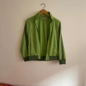 Grön Sweatshirt från Soc track jacket - Tröjan är liten i storleken. Storlek 146-152, men passar xs. OBS saknar dragkedja så går inte o stänga men är fin att ha öppen. Från Soc Y2k hoodie munkjacka