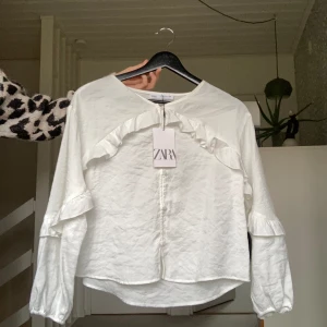Zara blus - Snygg vit blus med lite volanger från zara. Helt ny med lappen kvar. Säljer då den tyvärr är för kort i ärmarna. Nypris 259 ish💕 Hör av dig för fler bilder eller frågor