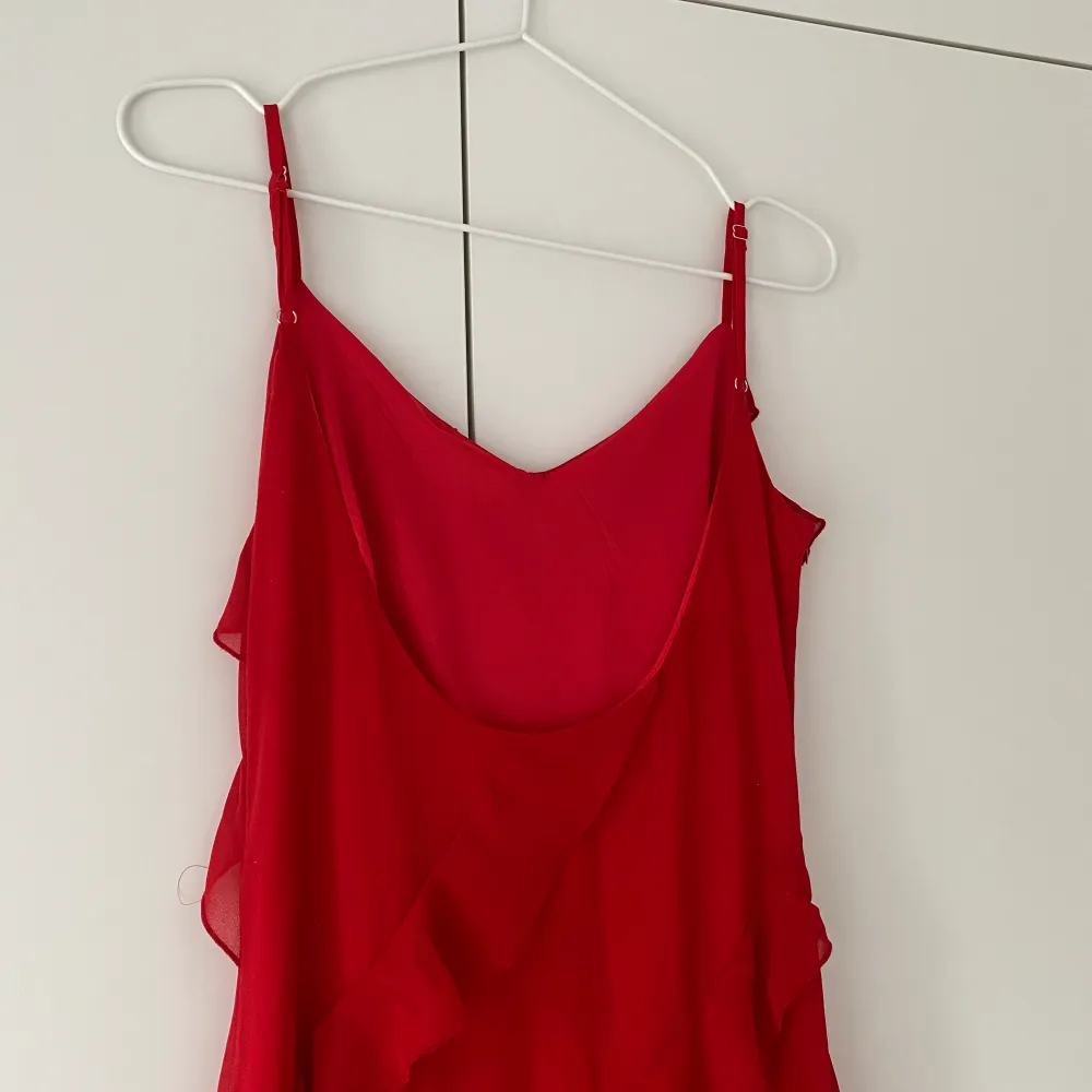 Röd långklänning med volanger och djupare rygg. Reglerbara band, underklänning och dragkedja i sidan. Oanvänd och i bra skick! Säljer då jag valde en annan färg. Str S men passar för XS/S ✨. Klänningar.