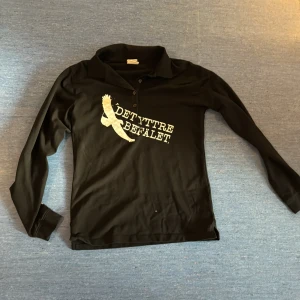 40. Svart Det yttre befälet Långarmad tröja - Det yttre befälet Merch gjord av bandet själva. Svart Långarmad tröja i bra skick. Det står tolk på ryggen vilket vi inte märkte när vi införskaffa tröjan men det borde gå att pilla bort.