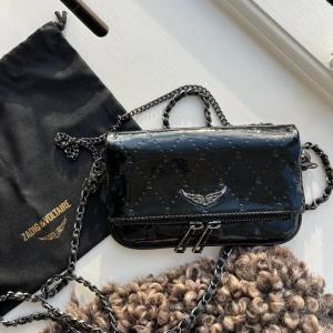 Zadig clutch väska - Intressekoll på min så coola och unika Zadig rock nano väska i lack med zv gravyr!!!! Från höstkollektionen 2021 och säljs inte längre, köptes för 2800kr. Dustbag kvitto finns pris kan diskuteras💗Små missfärgningar på vingarna o kedjan (märks knappt)