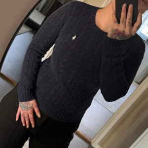 Kabelstickad ralph lauren tröja blå - Fin kabelstickad ralph lauren tröja i marinblå. 💙 Tröjan är i fint skick lite tvätt slitage se bild 2, vet inte hur jaha ja förklara men som om den är lite ”trött” i färgen. inget man tänker på när man han har den på sig. 🫶🏻 storlek S men jag är M 