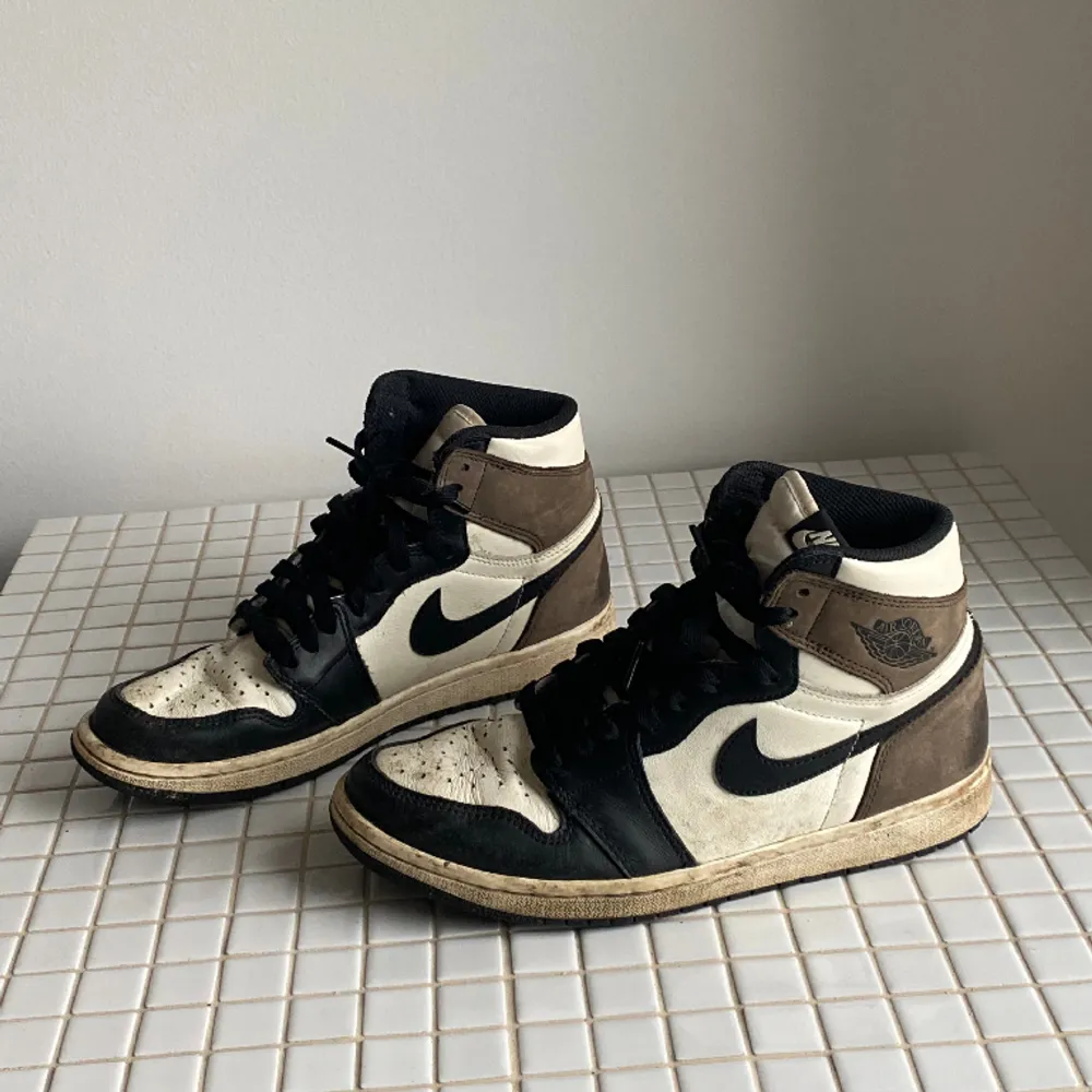 Höga Air Jordans 1 i mocha, storlek 41. Använt skick och lite smutsiga, men fortfarande fina. Köptes för 5500kr. PRIS KAN DISKUTERAS!💕. Skor.