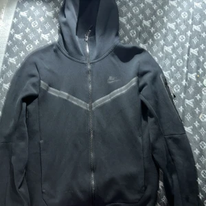 Nike tech hoodie - Tjena, säljer min tech hoodie som jag köpte för  ett år sedan och har använt bara ett fåtal gånger, den enda mindre skadan på tröjan är där man hänger upp tröjan i har lossnat men de har ingen påverkan på tröjan. Hör av er om funderingar om pris osv!