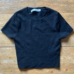 Svart kortärmad topp från Zara - En enkel och stilren svart kortärmad topp från Zara, i en kort passform. Toppen har en rund halsringning och är tillverkad i ett mjukt material. Knappt använd så i superskick 8/10