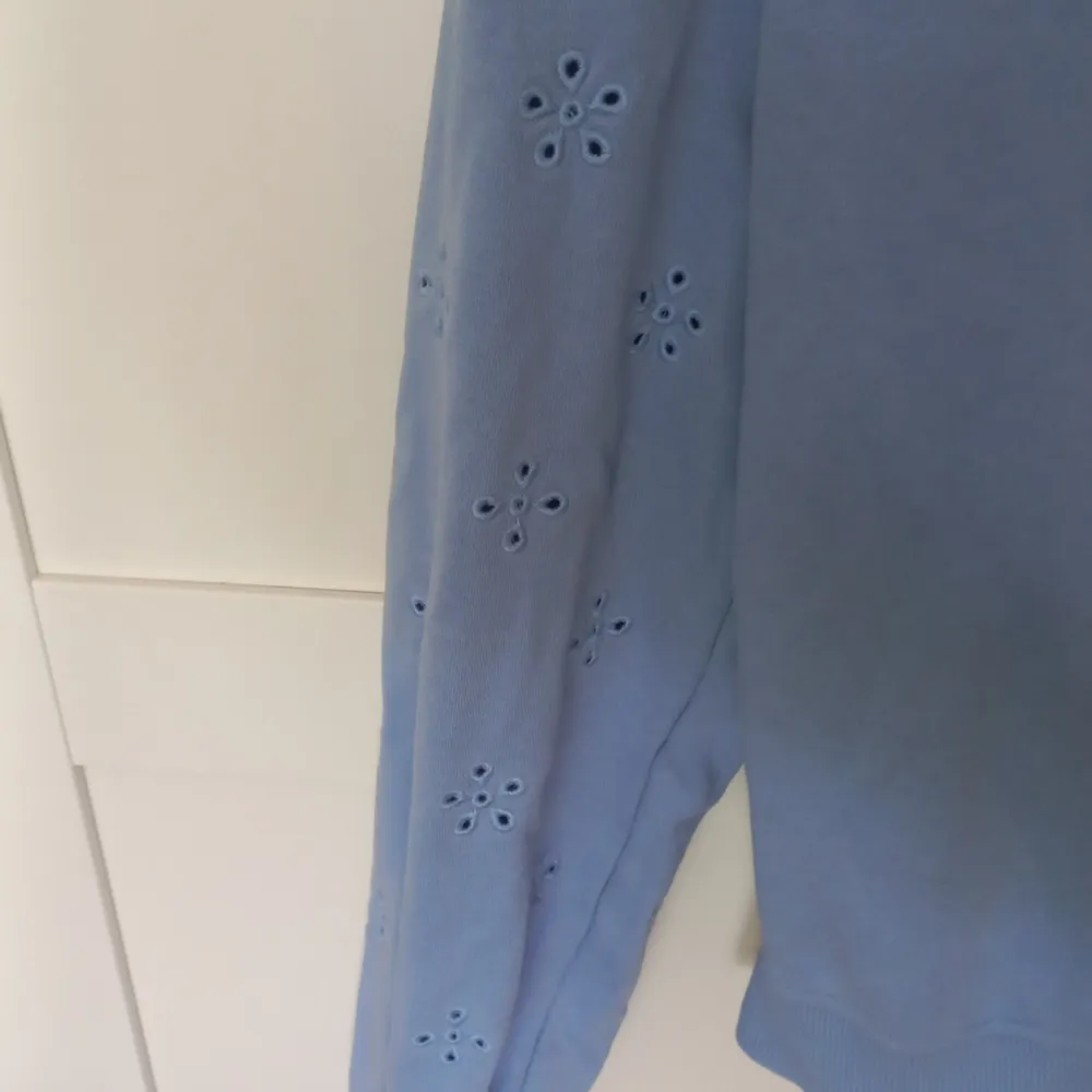 Säljer en blå tröja med blommor på ärmarna. I storlek xs från H&M. Använd 1 eller 2 gånger. Neuletakit & Villapaidat.