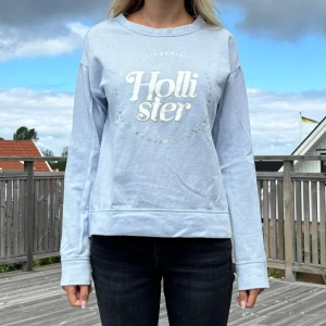 Tröja från Hollister - Hollister sweatshirt i ljusblå färg med silvriga och vita detaljer Storlek M