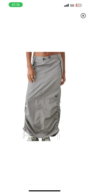 Lågmidjad kjol - Lågmidjad grå parachute kjol från urban outfitters storlek L, passar M också, reglerbar midja! Aldrig använd, nypris ca 699kr, säljes för 300kr