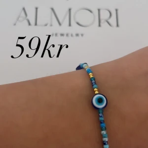 Blått armband från Almori - Ett vackert armband från Almori med blå pärlor och ögonmotiv. Armbandet har små blå och guldiga pärlor som ger det en färgglad och unik design.