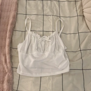 Vit croppat linne från Shein - Vitt croppat linne med rosett, från shein, storlek 10 år. Säljer för 30 kr. Använd fåtal gånger 