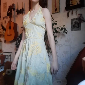Halterneck klänning med löv broderier! - Superläcker halterneck sommarklänning i ljus pastellgrön och med gula broderier av löv.♡ Öppen rygg och axelbanden knyts i nacken. Dragkedja där bak. Perfekt till sommaren eller midsommarfirande!☆ 