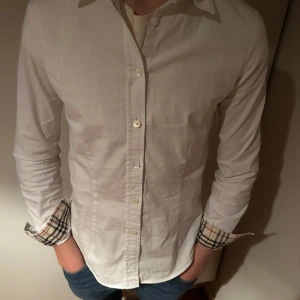 Burberry skjorta  - Hej, säljer nu denna riktigt snygga burberry skjorta. Skjortan är i bra skick och är ganska liten i storleken därför är den billig. Modellen på bilden är 169 cm lång. Skriv om du har några frågor.