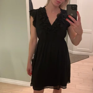 Söt svart klänning med volang från Zara - Svart klänning med volang och tre små knappar. Saknar ett litet skärp i midjan men superfin ändå! En L men passar även M! Stretchig i midjan så superskön