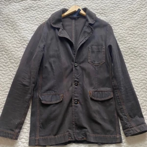 Mörkgrå jeans jacka - Schysst denim jacka i mörkgrå med orangea sömmar. Märket är Denim och storleken är M.