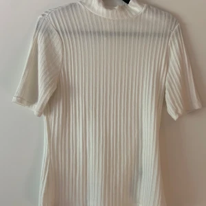 Vit ribbad tröja med hög krage från HM - Vit ribbad tröja med hög krage från HM i storlek S. Tröjan är i bra skick och har används ett fåtal gånger. 