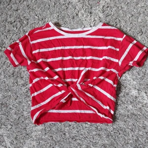 Randig tröja - Röd och vit randig croppad tröja med knyte fram i midjan. Sommrig tröja i storlek 134/140 men passar som en xxs. Säljer då den är lite liten för mig.