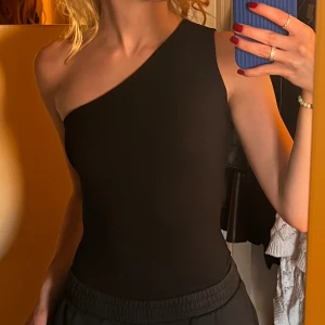 Oneshoulder body boohoo - Söt enaxlad body från boohoo 💕  Inga metallknappar som knäpps, utan bara tyg - jätteskönt! Använd fåtalet gånger. Stretchig i materialet så skulle säga att den passar 32-34, möjligen även 36!