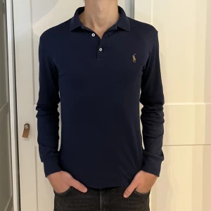 Långärmad Ralph Lauren piké  - Långärmad Ralph Lauren piké i färgen mörkblå. Inga defekter på tröjan. Size S (slim fit) modellen är 177cm. Hör av dig vid funderingar!
