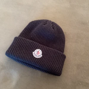 Svart moncler mössa - Hej säljer nu min moncler mössa. Jag har inte behov av en mössa just nu men eftersom sommaren börjar ta slut och hösten är runt hörnet så är det ganska bra att ha en. Mössan har scan och är aldrig använd.