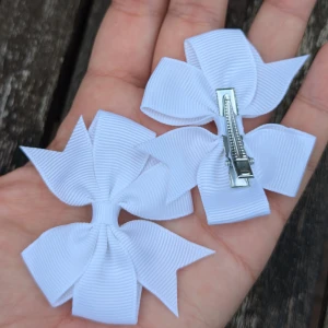 Vita rosett hårklämmor - Ett set med vita rosett hårklämmor. Rosetterna är tillverkade av ett ribbat material och fästs med en metallklämma. Perfekta för att dekorera håret och ge en söt touch till vilken frisyr som helst.