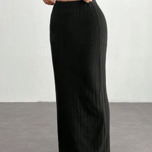 Svart ribbad långkjol - Säljer en svart ribbad långkjol med tight passform. Kjolen har en enkel och stilren design som passar perfekt till många olika outfits. Materialet är stretchigt och bekvämt. Helt oanvänd i storlek XS. 