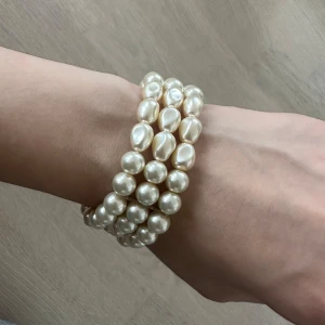 Pärlarmband i flera rader - Snyggt armband med flera rader vita pärlor. Armbandet har elastisk passform och ger en elegant look med sina glansiga pärlor. Perfekt accessoar för att lyfta din outfit.