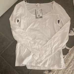 Vit långärmad topp från H&M - Säljer en enkel och stilren vit långärmad topp från H&M. (Aldrig använd) 