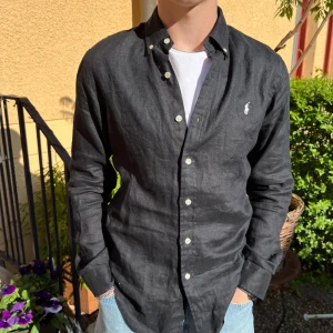 Ralph Lauren Linneskjorta - Tjena! Säljer en riktigt snygg och stilig Ralph Lauern linneskjorta. Den är i nyskick, kanppt använd 10/10. Skjortan är i färgen svart och märket är vitt. Storlek M. Den är perfekt nu till  sommaren☀️ Nypris runt 1800 kr Hör av dig vid funderingar🙌