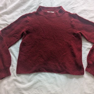 Vinröd stickad tröja från Chloé - Mysig vinröd stickad tröja från Chloé med hög krage och lång ärm. Perfekt för kyliga dagar och enkel att matcha med jeans eller kjol. Tröjan har en klassisk och tidlös design.