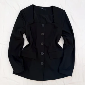 Svart Figursydd Kavaj från Gina Tricot - Super snygg svart kavaj från Gina Tricot med markerad midja, figursydd passform och fem knappar framtill. Perfekt för en dressad look.