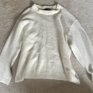 Vit stickad tröja från 157 - Mysig vit stickad tröja från 157 med lång ärm och ribbade detaljer vid hals, ärmslut och nederkant. 🤍