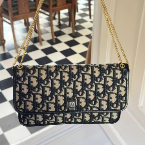 Monogramväska med gulddetaljer - Så snygg och klassisk axelväska/kuvertväska i blå och crémefärgat monogrammönster. Använd men i fint vintage skick. Gulddetaljerna är massiva och inte slitna. Man får plats med mycket i den även om den är nätt. Skicka privat för fler bilder eller info 🌺