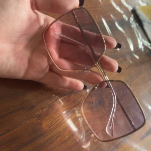 Stora fyrkantiga solglasögon med guldiga bågar - Säljer ett par oversized solglasögon med tunna guldiga metallbågar och stora fyrkantiga linser i en svagt rosa ton. Perfekta för dig som vill sticka ut med en trendig accessoar.