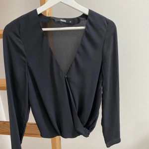 Svart omlottopp från Bik Bok - Säljer en svart omlottopp från Bik Bok med v-ringning och lång ärm. 