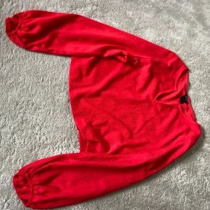 Röd croppad tröja med ballongärmar - Säljer en röd croppad tröja med långa ballongärmar och rund halsringning. Tröjan har en mjuk struktur och resår vid ärmsluten för en snygg passform. Perfekt för dig som vill sticka ut med färg! Skriv för fler bilder🥰