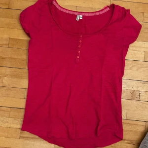 Rosa topp med knappar - Säljer en rosa topp i storlek S (36/38). Toppen har rund halsringning med spetskant och knappar framtill. Aldrig använd. 